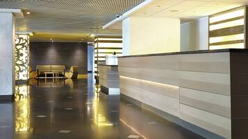 Un hall d’entrée moderne avec un comptoir d’accueil, un espace salon et un plafond orné de motifs.