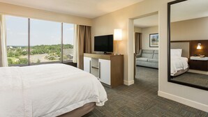 Habitación de hotel con una cama grande, televisión, escritorio y vistas a la ciudad.