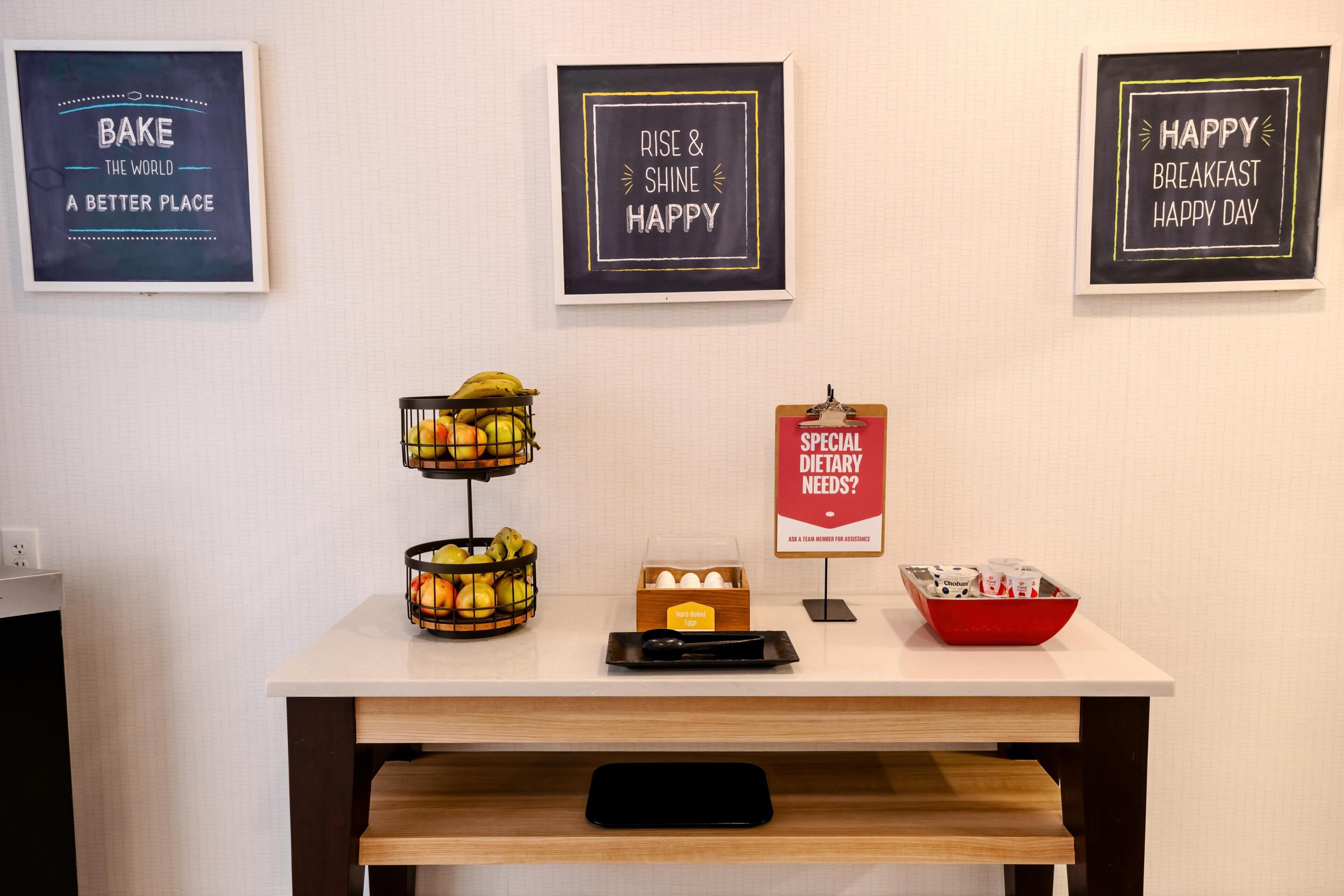 A kitchen counter with a fruit basket, a tray of eggs, and a sign about dietary needs.