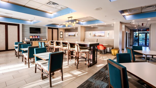 Un moderno vestíbulo de hotel con comedor, televisor de pantalla plana y estación de café.
