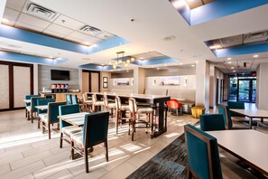 A modern hotel lobby with a dining area, a flat-screen TV, and a coffee station. - Hampton Inn Manassas (Manassas)