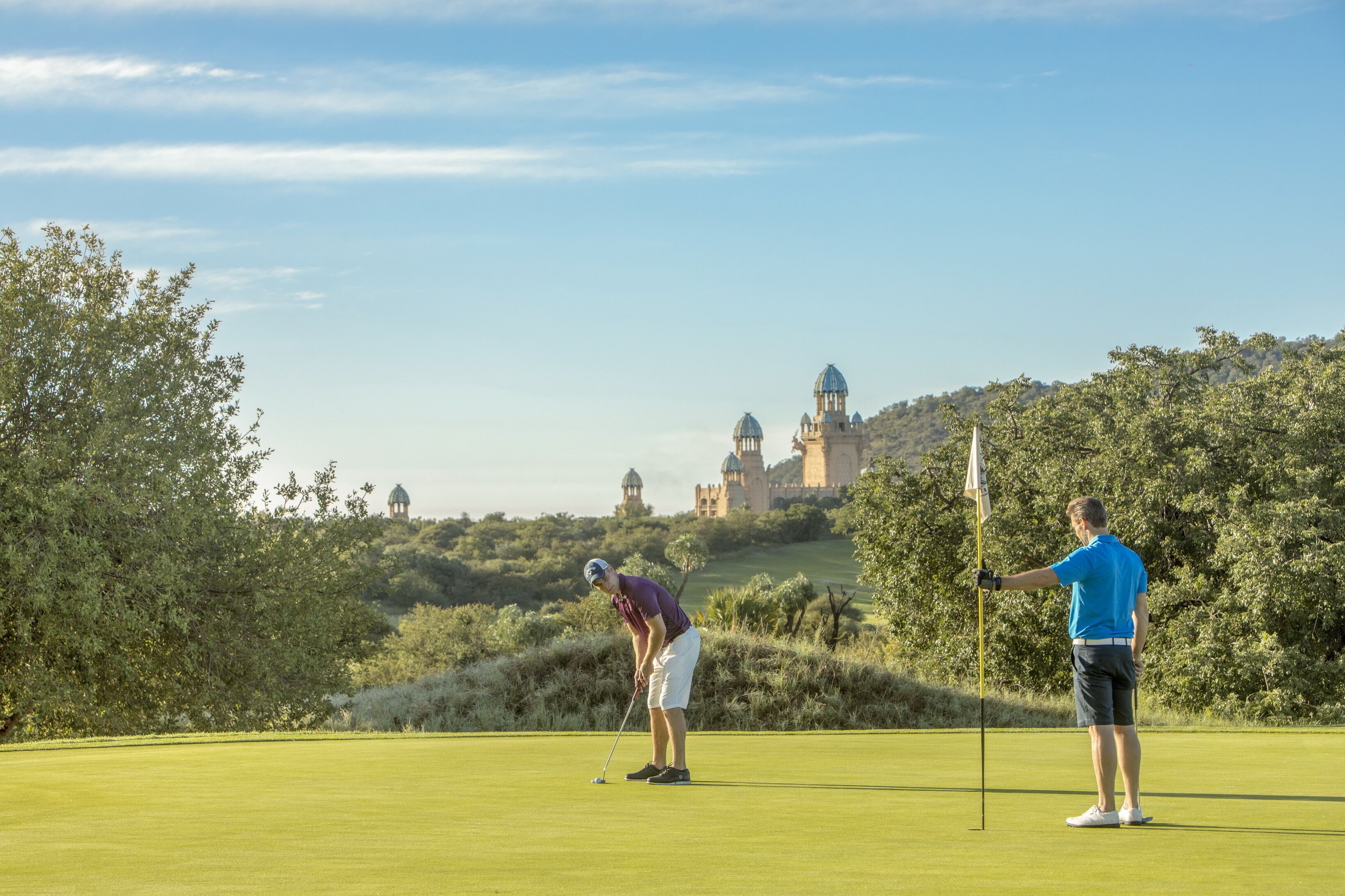 Een golfbaan met een kasteel op de achtergrond.