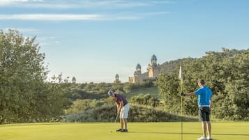Een golfbaan met een kasteel op de achtergrond.