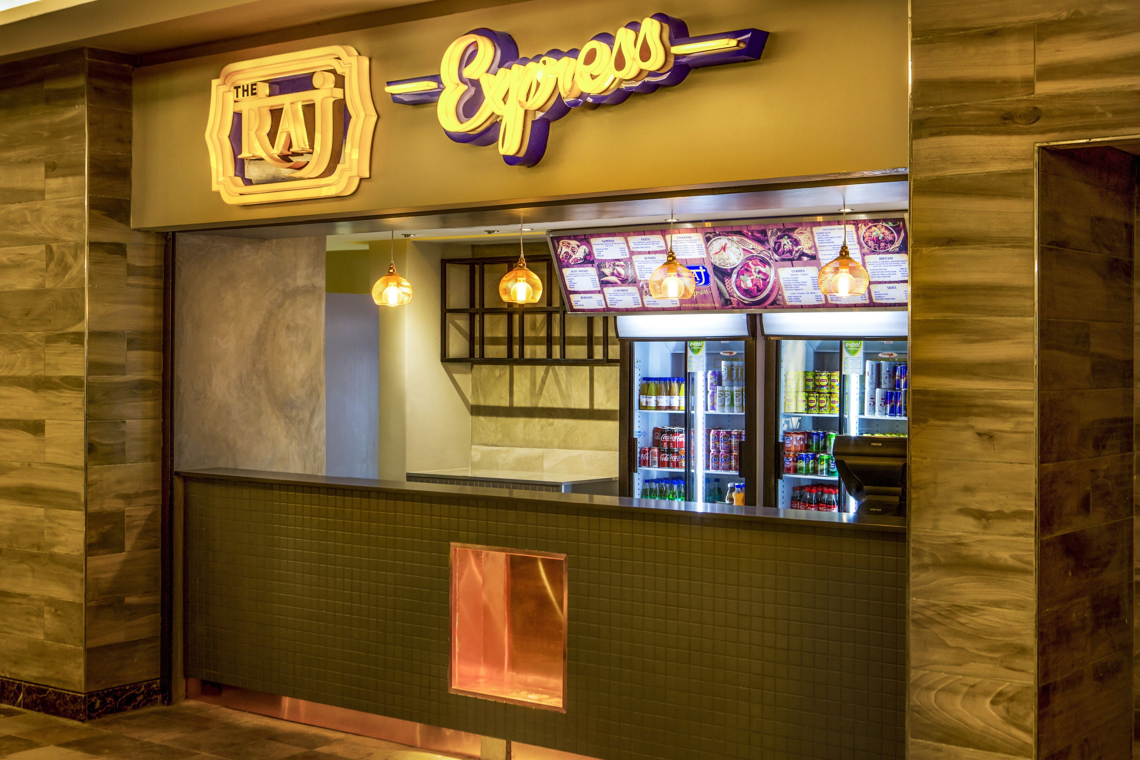 Um restaurante com letreiro de neon, quadro de cardápio e balcão refrigerado.
