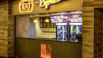Um restaurante com letreiro de neon, quadro de cardápio e balcão refrigerado.