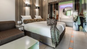 Une chambre moderne avec un grand lit, une table de chevet, un canapé et une douche en verre.