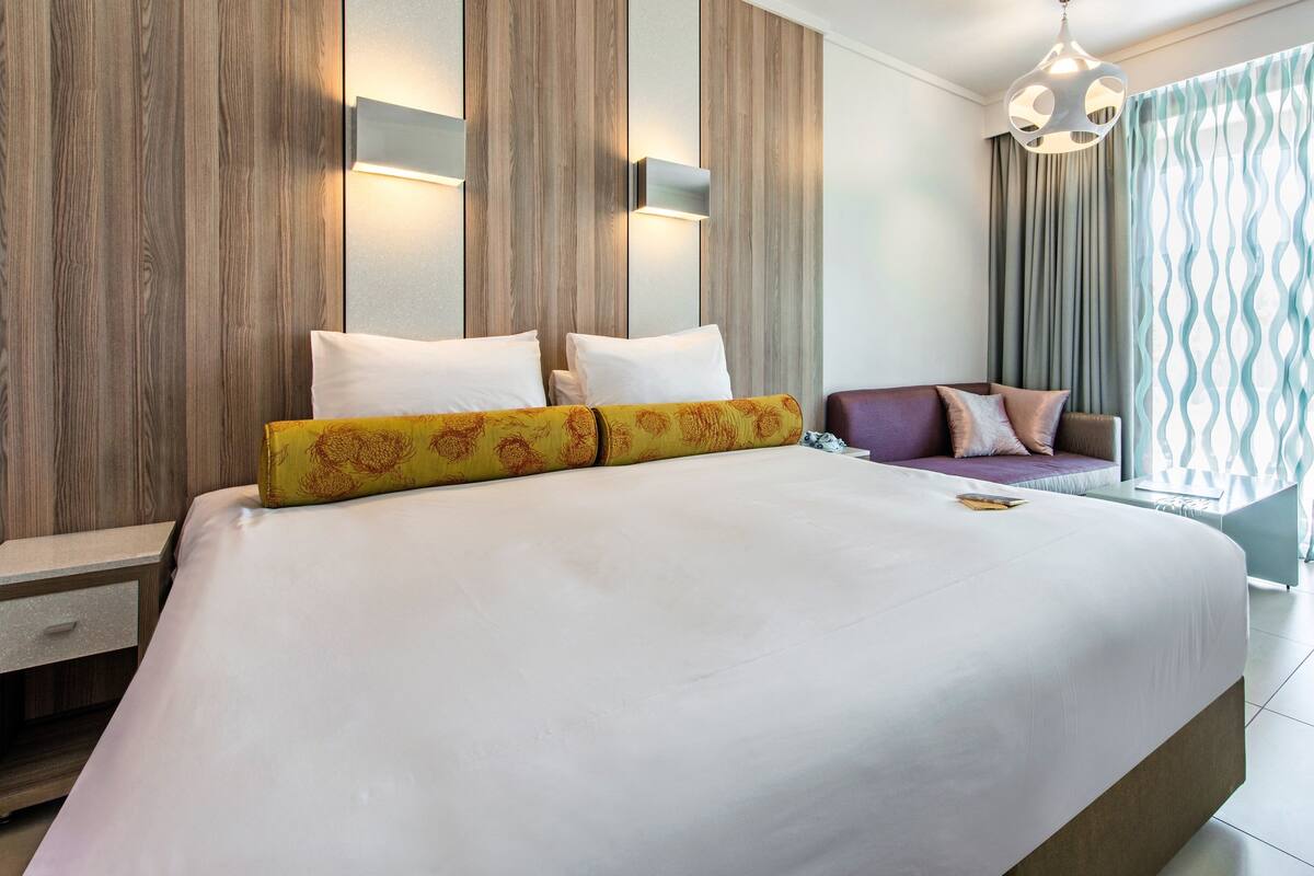 Une chambre d’hôtel moderne, dotée d’un grand lit, d’un canapé et d’une table de chevet.