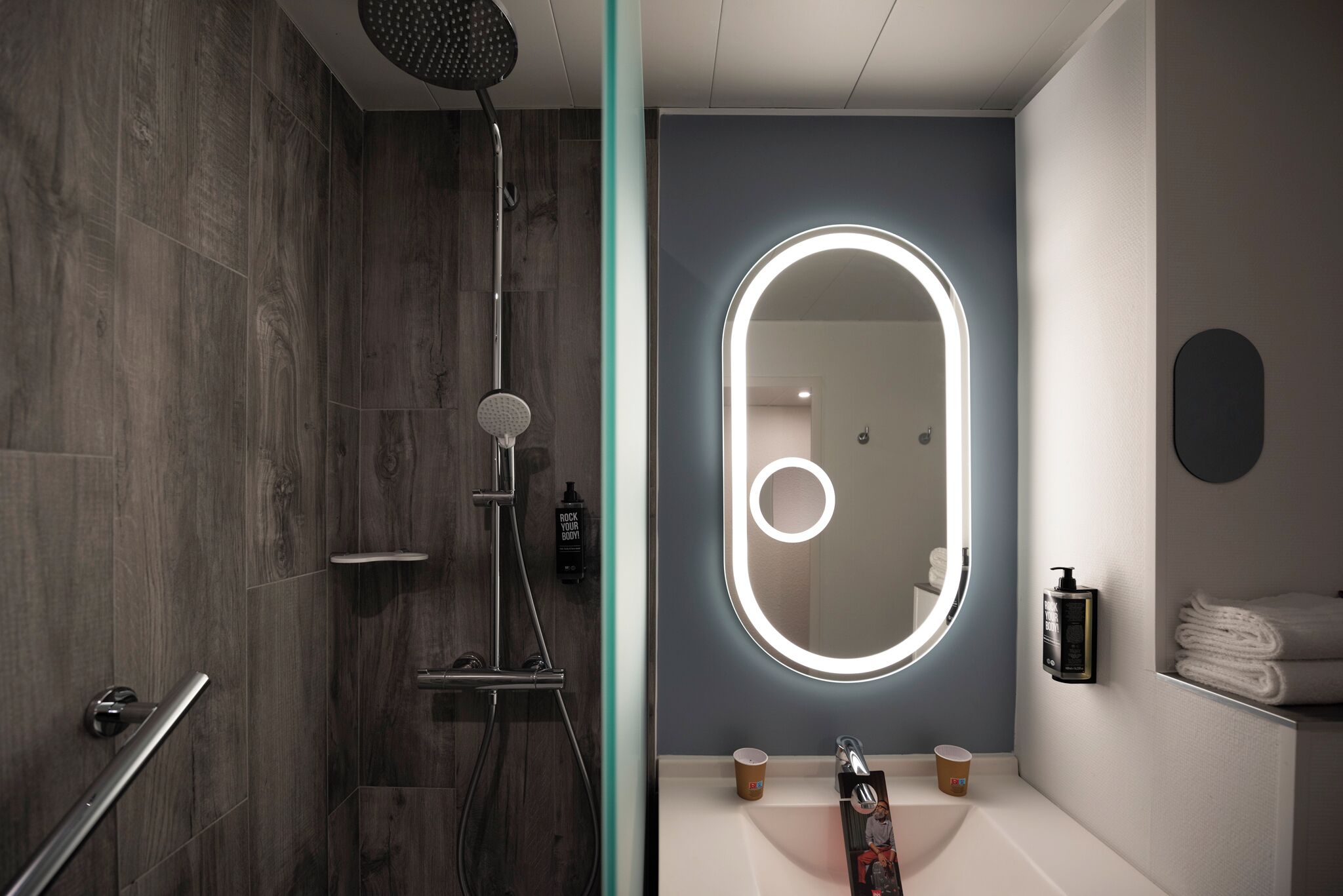 A modern bathroom with a shower, a vanity with a mirror, and a towel rack.