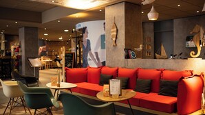 A modern interior with a red sofa, green chairs, and a wooden table.