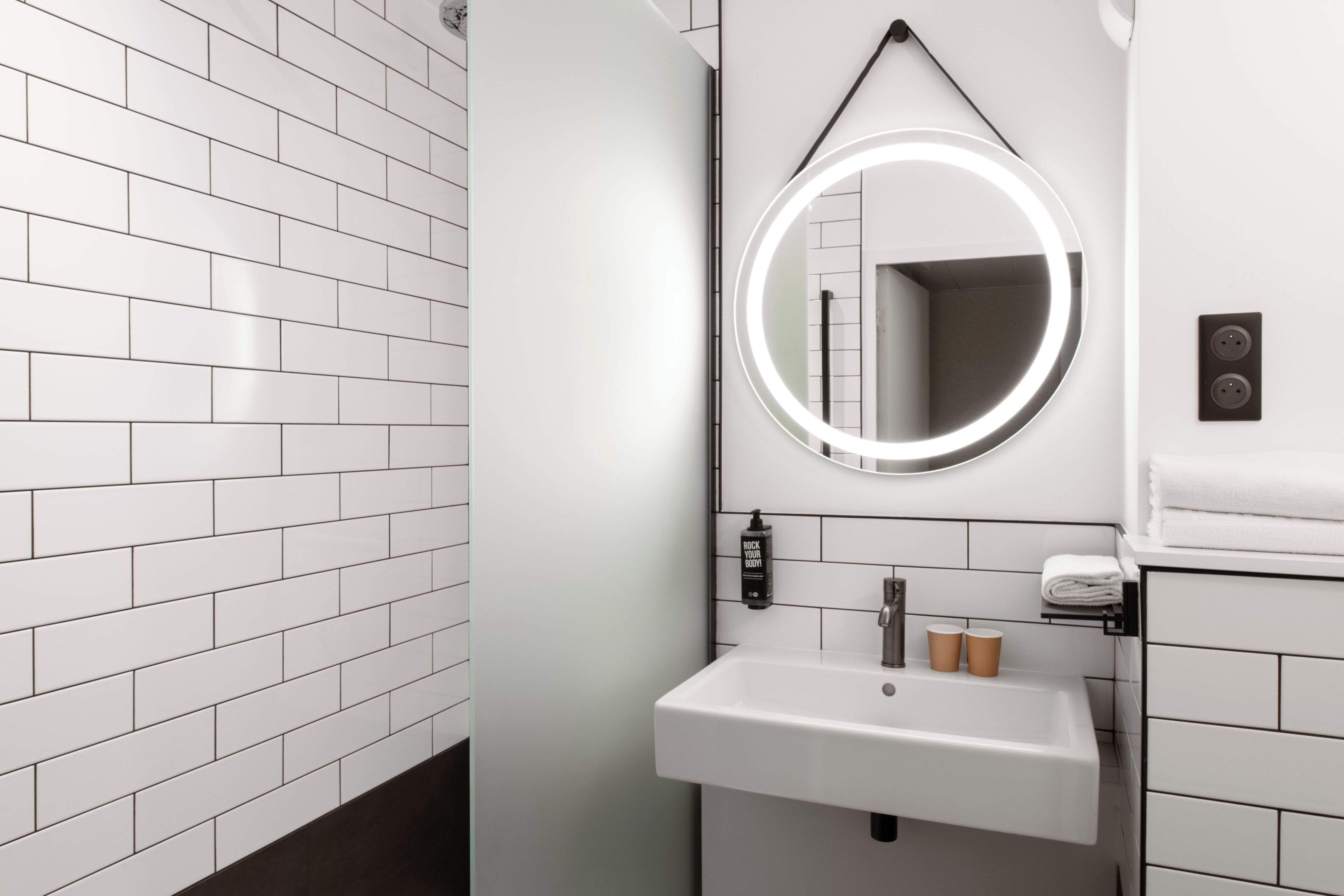 Een badkamer met witte metro tegels, een wastafel met spiegel en een handdoekhouder.