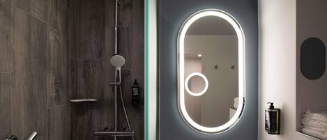 A modern bathroom with a shower, a vanity with a mirror, and a towel rack.