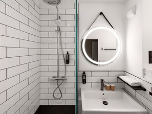 Une salle de bain moderne équipée d’une douche, d’un lavabo, d’un miroir et d’un porte-serviettes.