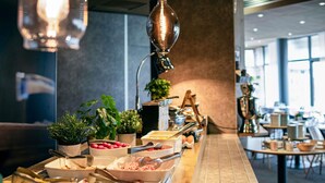 A buffet setup with various food items, utensils, and decorative plants.