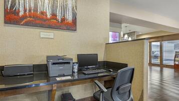 Una recepción de hotel con computadora, impresora y una silla.