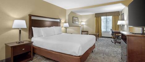 A hotel room with a large bed, two bedside tables with lamps, a desk, and a chair.