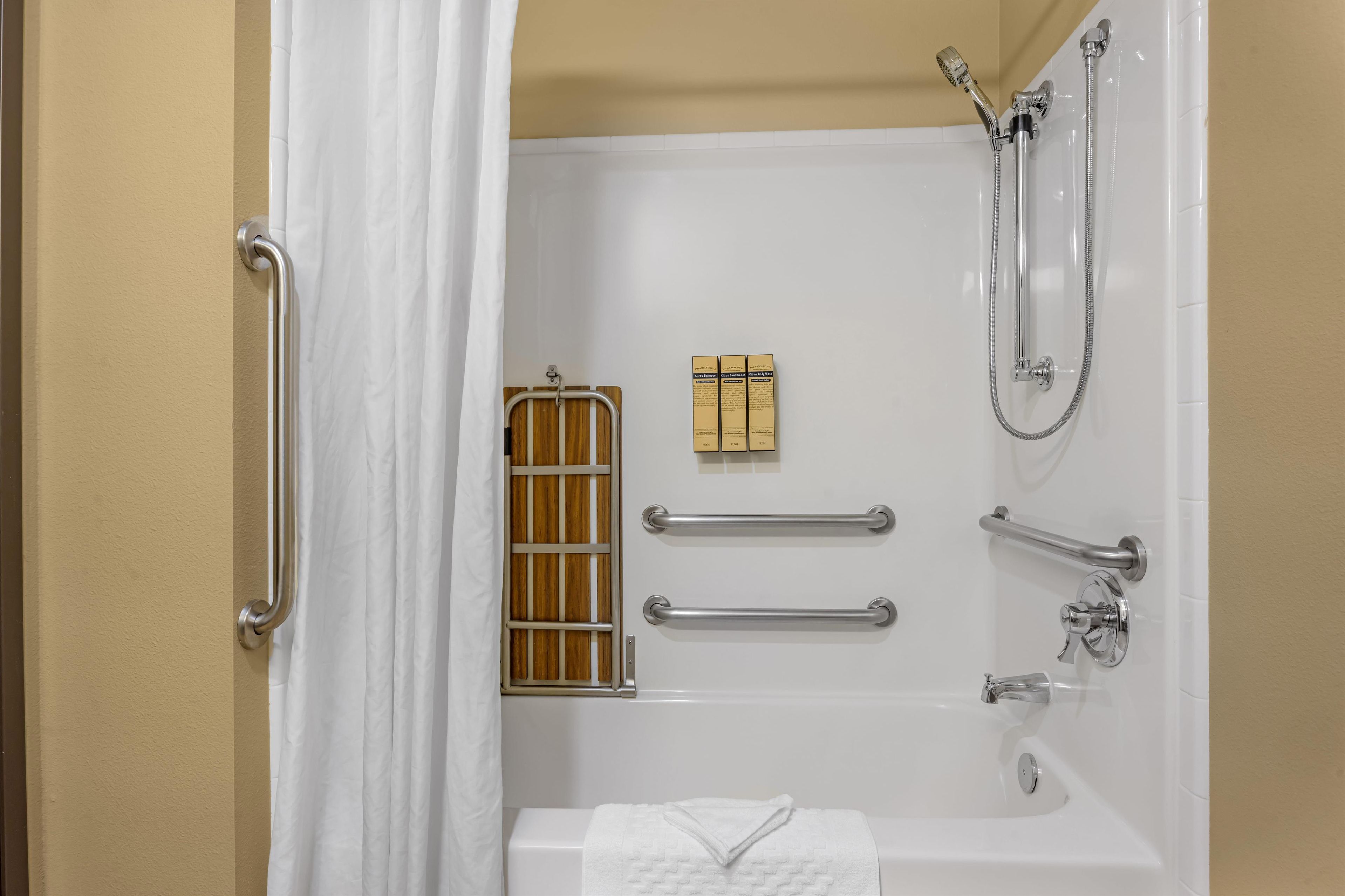 A bathroom with a bathtub, shower, and grab bars.