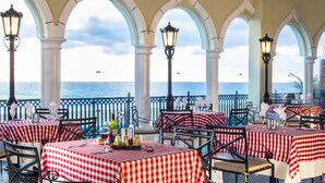 Un ristorante sul mare con tovaglie a quadretti, colonne bianche e sedie in metallo nero.
