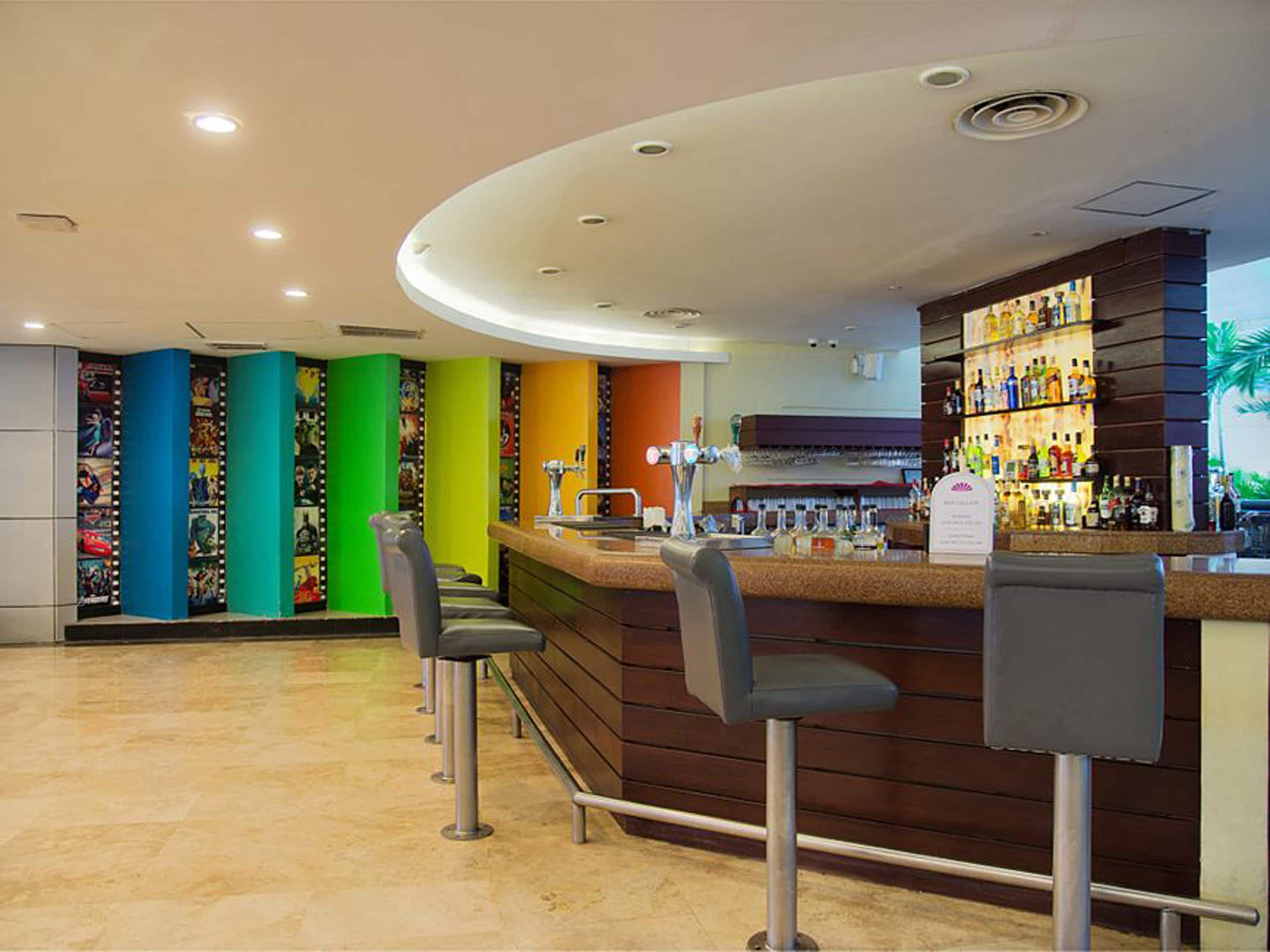 A bar area with a counter, stools, and a wall of colorful posters.