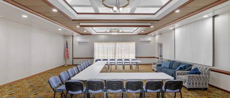 A conference room with a long table, chairs, a sofa, and a flag.