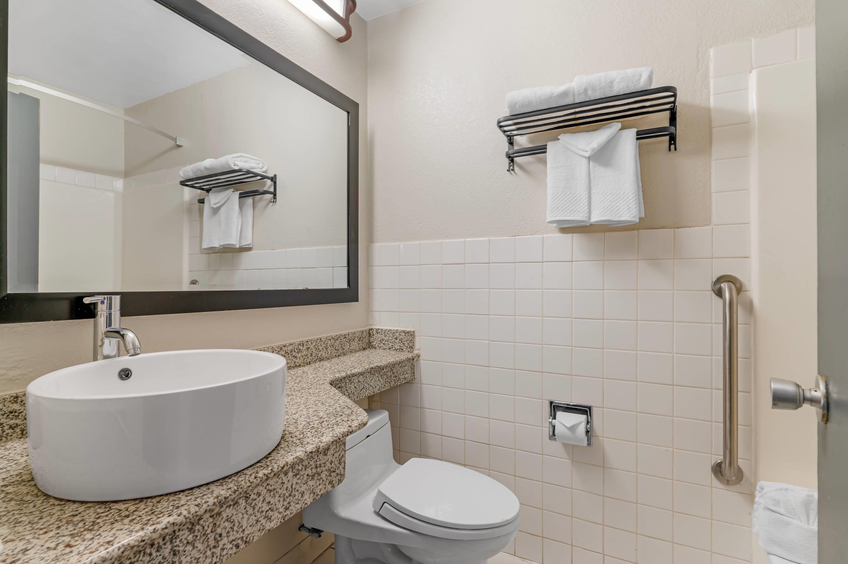 A bathroom with a white sink, toilet, and a towel rack.