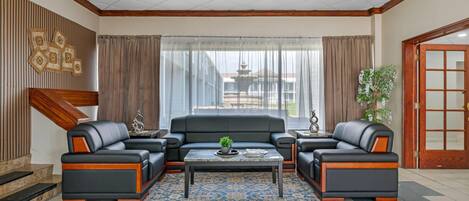 A modern living room with a sofa set, a coffee table, and a view of a building outside.