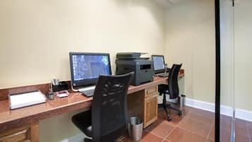 A workspace with two desktop computers, a printer, and office chairs.