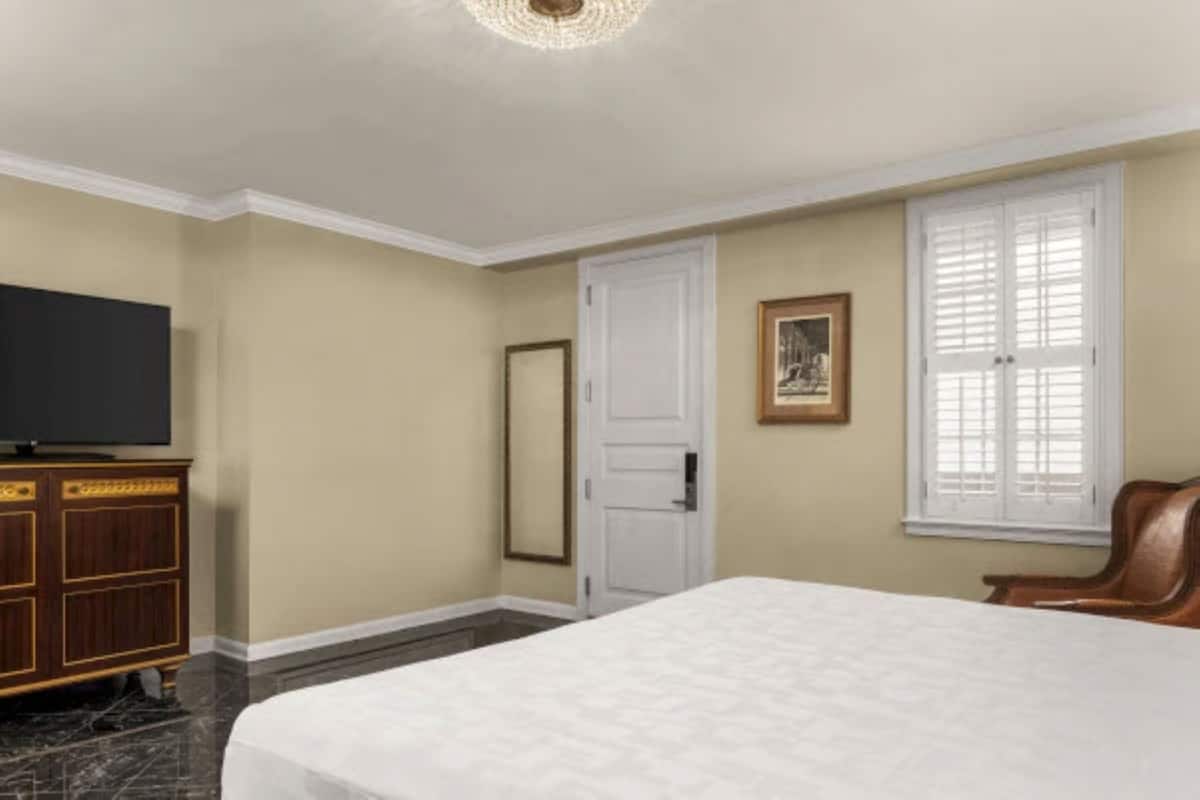 Une chambre d’hôtel avec un lit, une télévision, une armoire, une porte et une fenêtre.