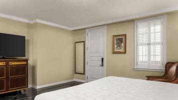 A hotel room with a bed, a television, a wardrobe, a door, and a window.