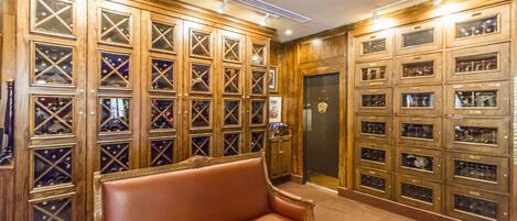 A lobby with a brown leather sofa, wooden wine cabinets, and a reception desk.