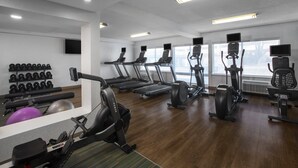 A modern gym with treadmills, elliptical machines, and free weights.