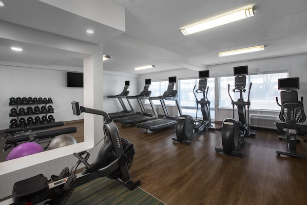 A modern gym with treadmills, elliptical machines, and free weights.