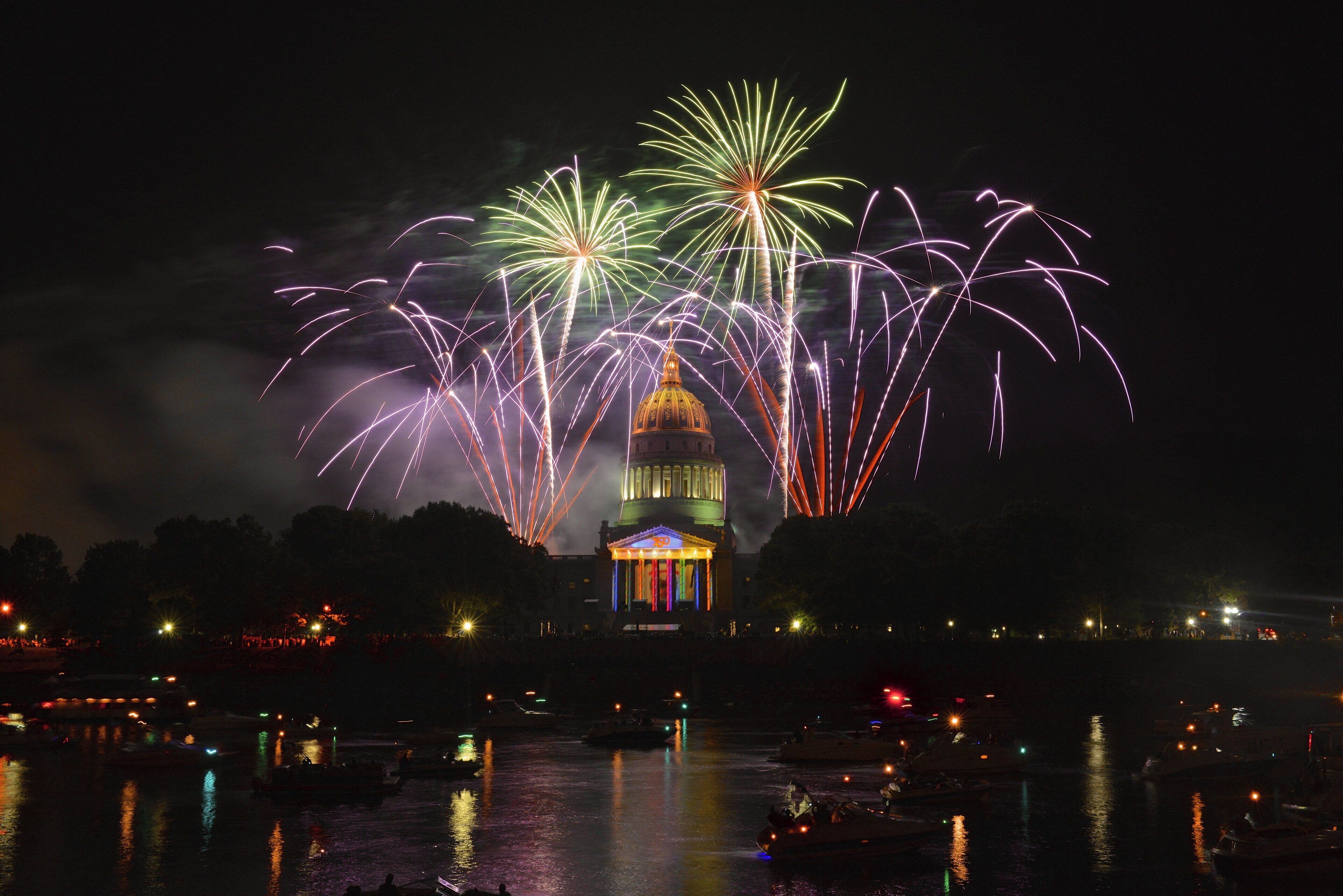 A nighttime view of a waterfront with fireworks display and a prominent building with a dome.