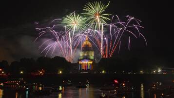 A nighttime view of a waterfront with fireworks display and a prominent building with a dome.