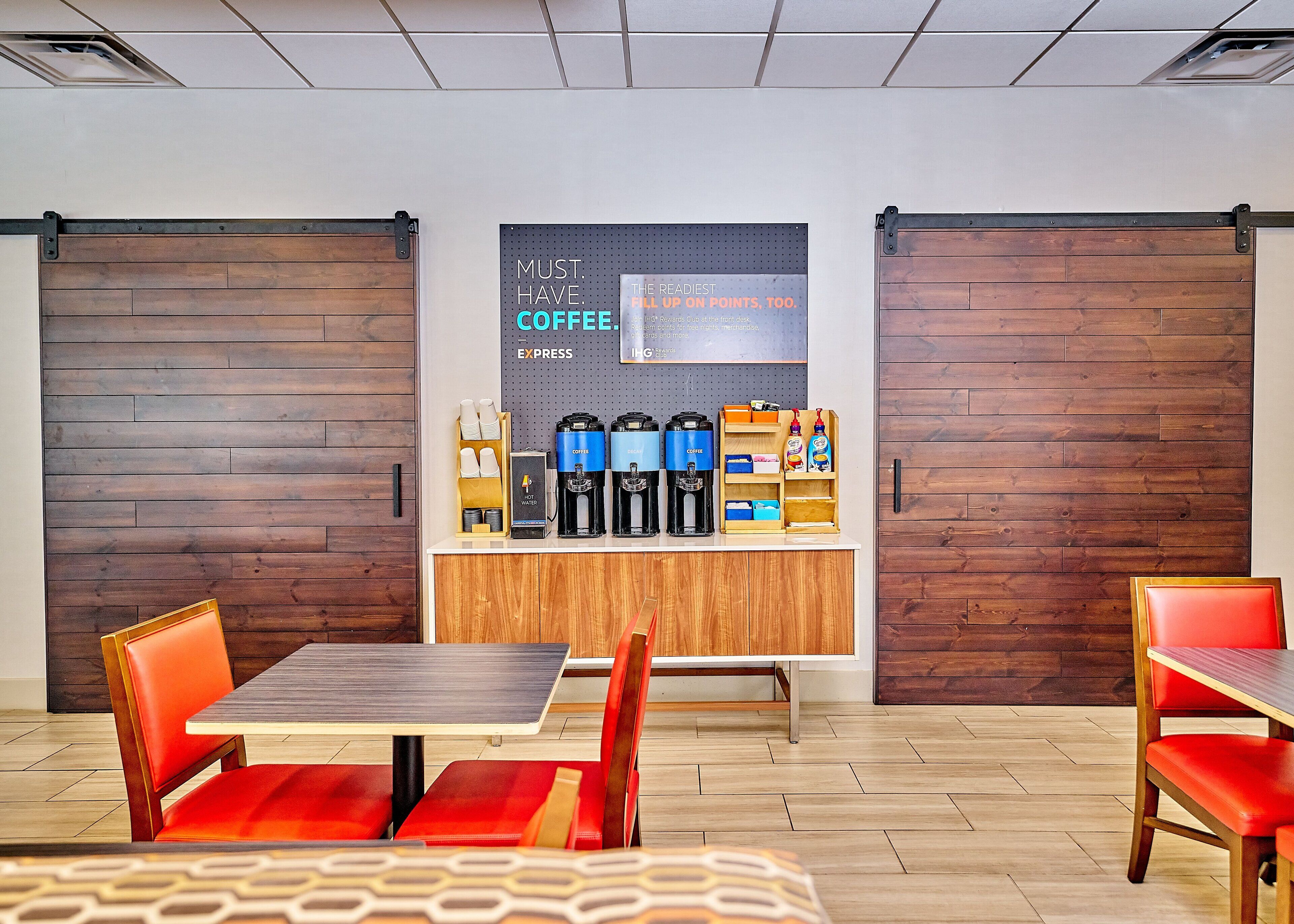 A modern coffee bar with espresso machines, a coffee station, and a sign promoting coffee.