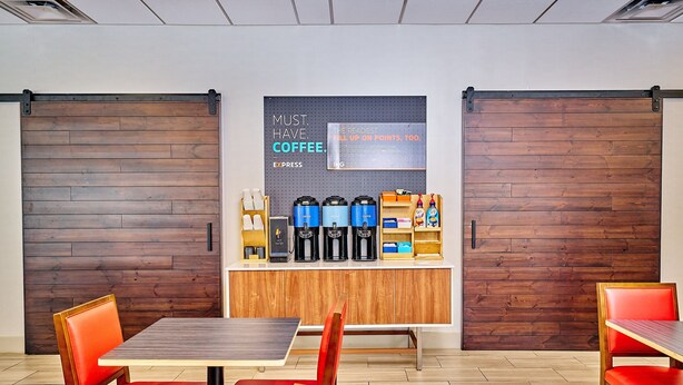 A modern coffee bar with espresso machines, a coffee station, and a sign promoting coffee.