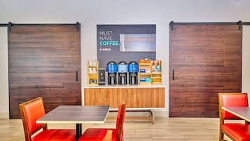 A modern coffee bar with espresso machines, a coffee station, and a sign promoting coffee.