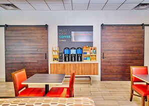 A modern coffee bar with espresso machines, a coffee station, and a sign promoting coffee. - Holiday Inn Express Charleston-Civic Center by IHG (Charleston)