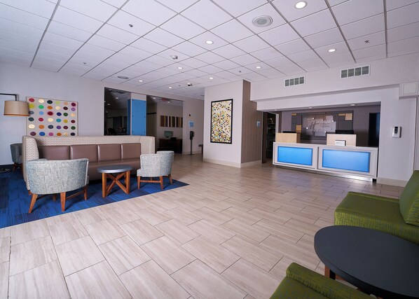 A modern lobby with a reception desk, seating area, and a colorful wall decoration.