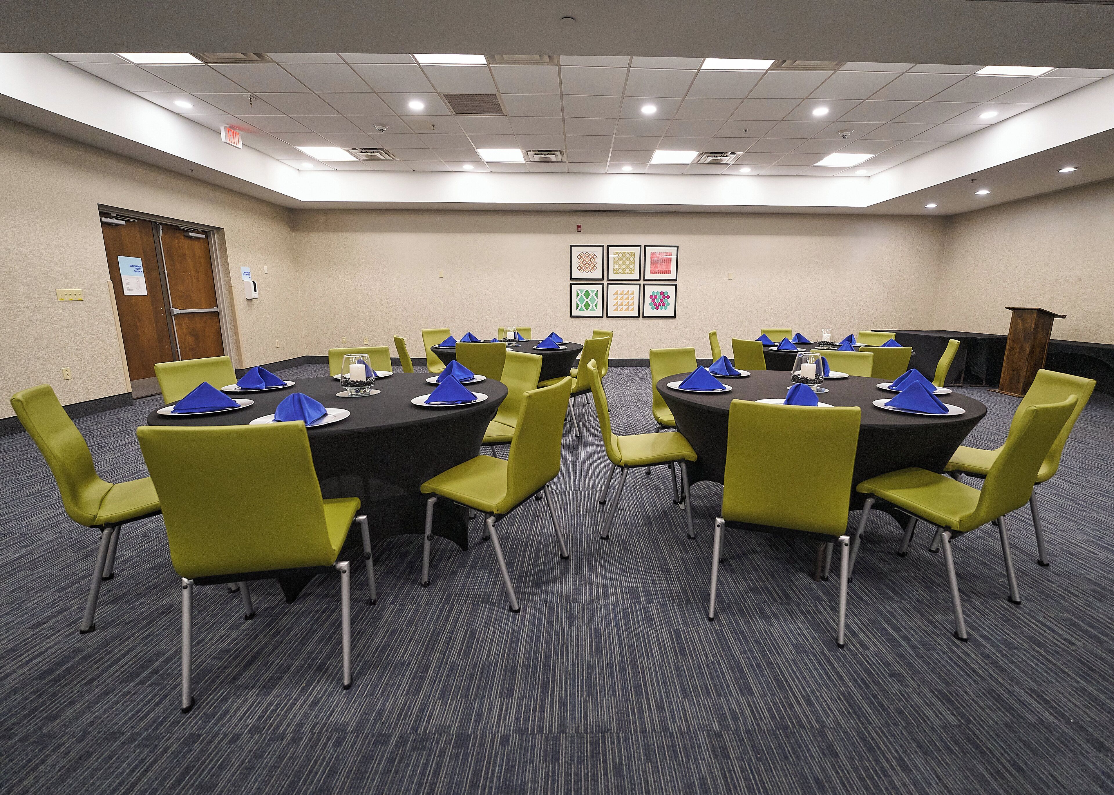 A conference room with multiple tables and chairs, equipped with nameplates and blue napkins.