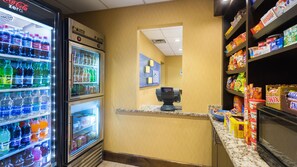 Un espace de vente proposant un réfrigérateur rempli de Coca-Cola Zéro, un distributeur de barres chocolatées Twix, ainsi qu’une variété de collations et de boissons.