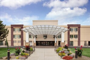 A hotel entrance with a covered walkway, a landscaped garden, and a clear sky. - Holiday Inn Downtown - Missoula by IHG (Missoula)