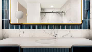 A modern bathroom with a large mirror, a sink, and a shower.