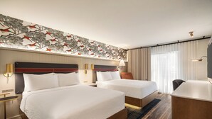 A hotel room with two beds, a desk, and a headboard with a floral design. - Holiday Inn Downtown - Missoula by IHG (Missoula)