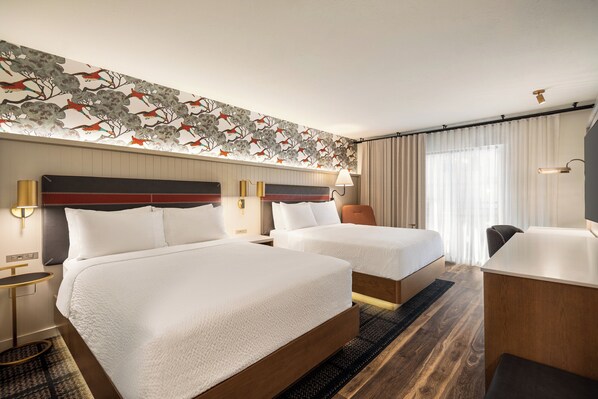 A hotel room with two beds, a desk, and a headboard with a floral design. - Holiday Inn Downtown - Missoula by IHG (Missoula)