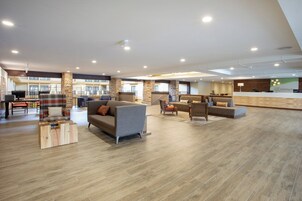 A spacious lobby with multiple seating areas, a reception desk, and a staircase leading to upper floors.