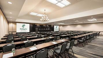A conference room with long tables, chairs, and a large screen displaying 'Holiday Inn Missoula Downtown'.