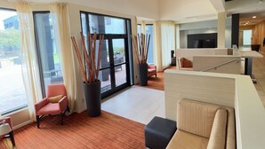 A modern hotel lobby with a seating area, large windows, and a view of the outdoors. - Super 8 by Wyndham Dallas Love Field Airport (Dallas)