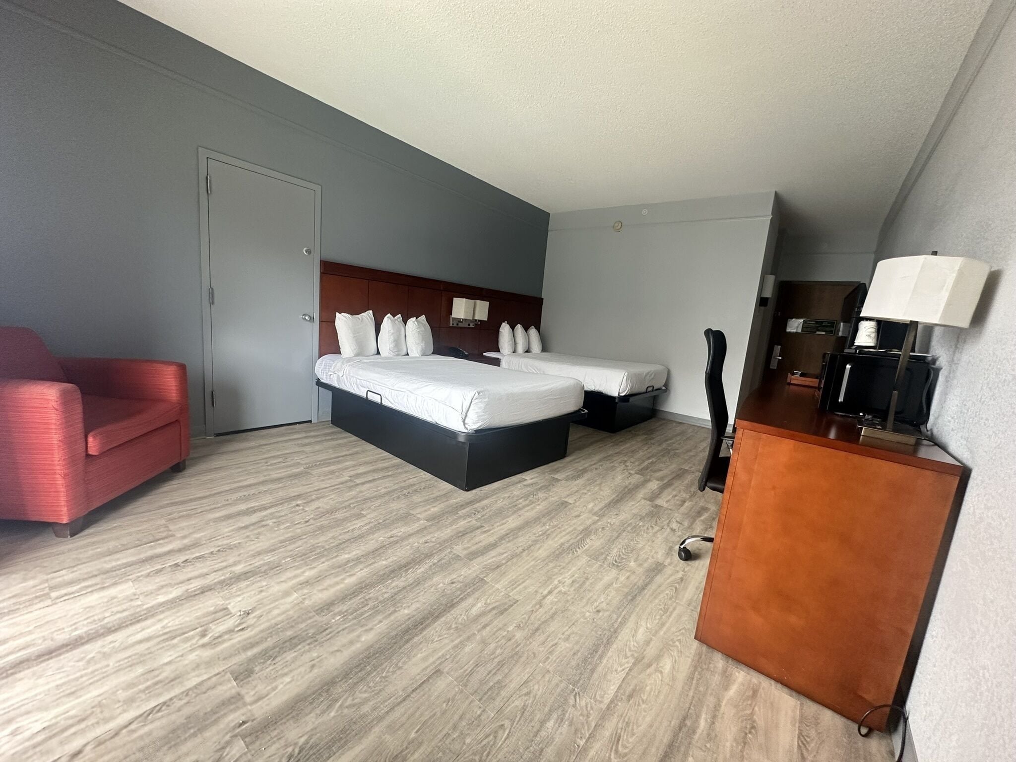 A hotel room with a large bed, a desk, a chair, and a red sofa.