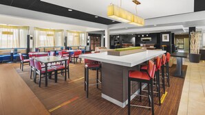 A modern restaurant with a central island, red and black chairs, and a bar area. - Super 8 by Wyndham Dallas Love Field Airport (Dallas)