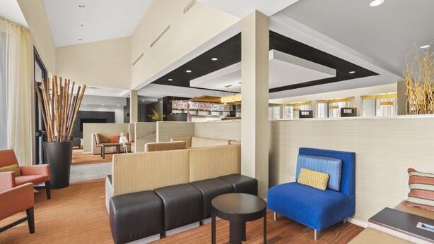 A modern hotel lobby with a seating area, a reception desk, and a view into the dining area. - Super 8 by Wyndham Dallas Love Field Airport (Dallas)